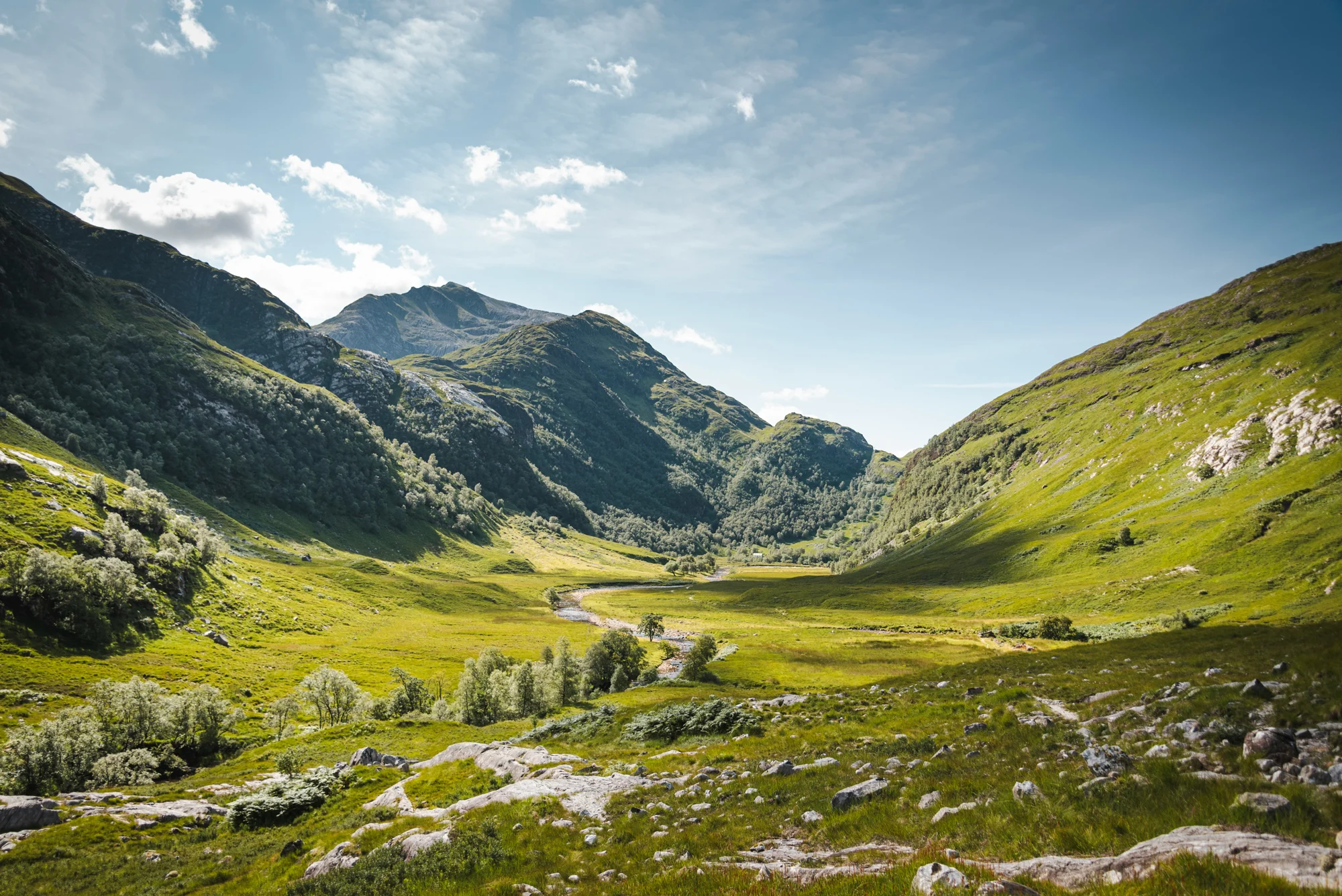 Sunlight on the green slopes and dramatic mountains of Glencoe