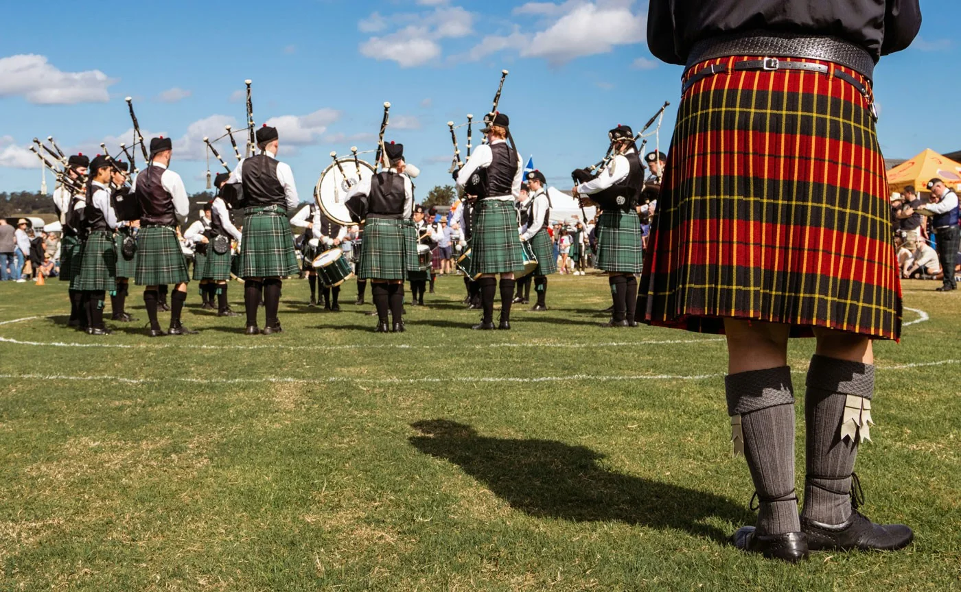 Bagpipers wearing tartan kilts performing outdoors.