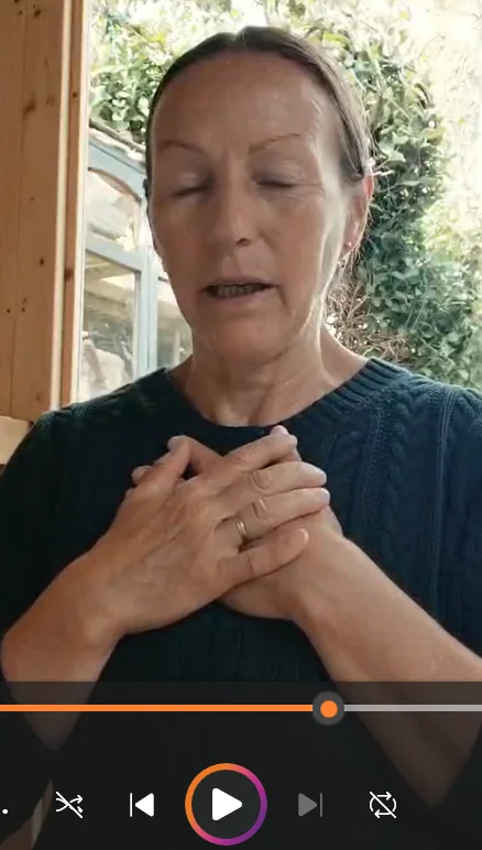 Still from Sandrine Gardner’s grounding meditation, with her eyes closed and hands resting over her chest.